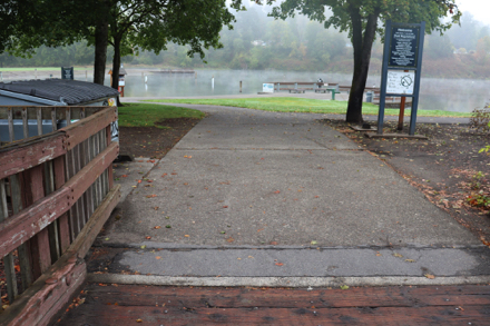 Approaching Pond – trash can – rules – intersecting hard surface pathways – pier with railing at pond – benches – drinking fountain